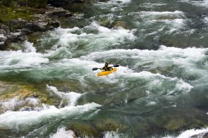 The beautiful scenery of the rafting on the mountain river stream flowing down between huge stones