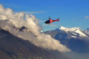 Helicopter flying among the clouds above the snow-capped mountains A helicopter flying among the clouds above the snow-capped mountains